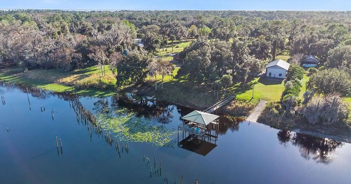 Aerial view of lakefront property with covered dock and wooded acreage near Haines City Florida in Polk County