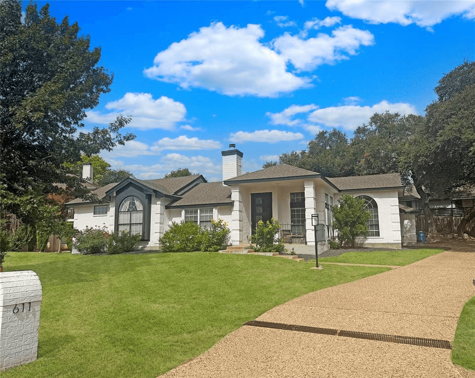 Single-story Texas limestone home with mature trees and landscaped front yard in established residential neighborhood