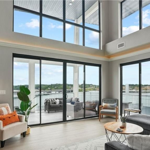 Circular interior living area photo: modern living room with floor-to-ceiling windows overlooking a waterfront, bright and airy