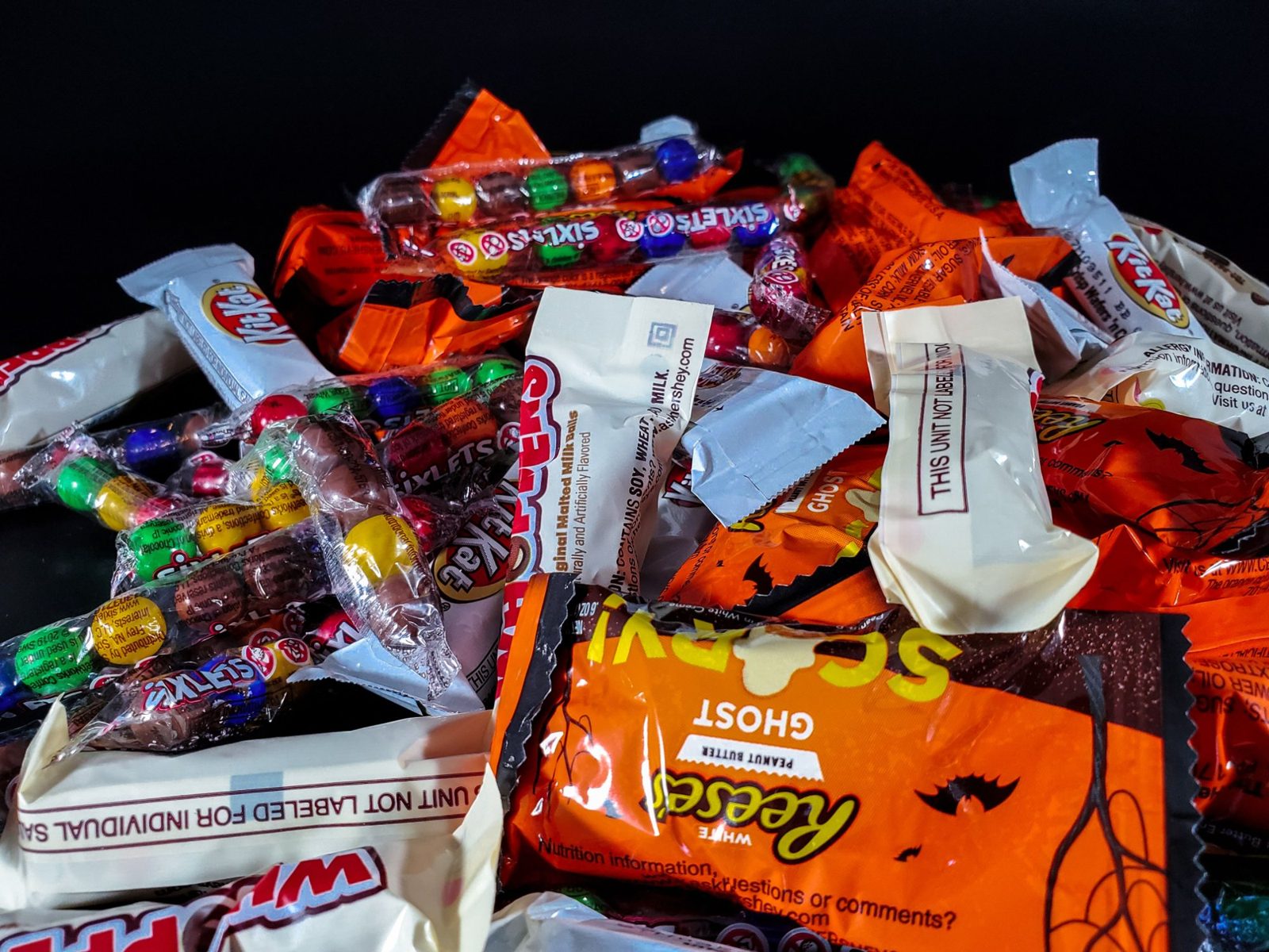 Pile of Halloween candy including Kit Kat, Reese's and Sixlets