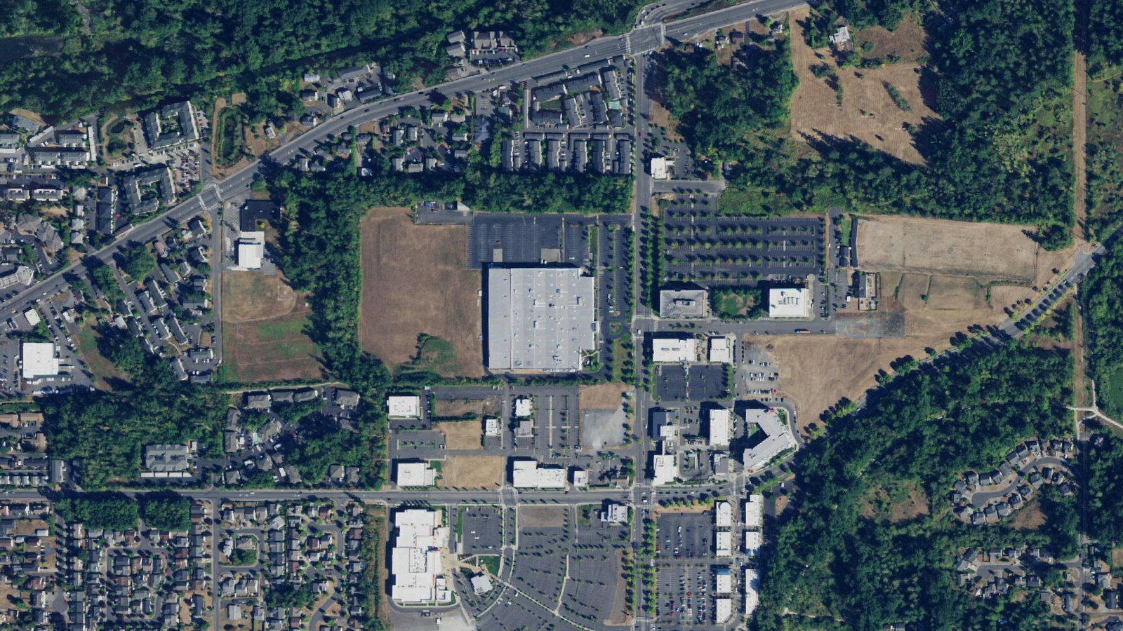 A 2017 aerial photo looking straight down on the Barkley Village area of Bellingham, with stores, parking lots, apartments and open fields.