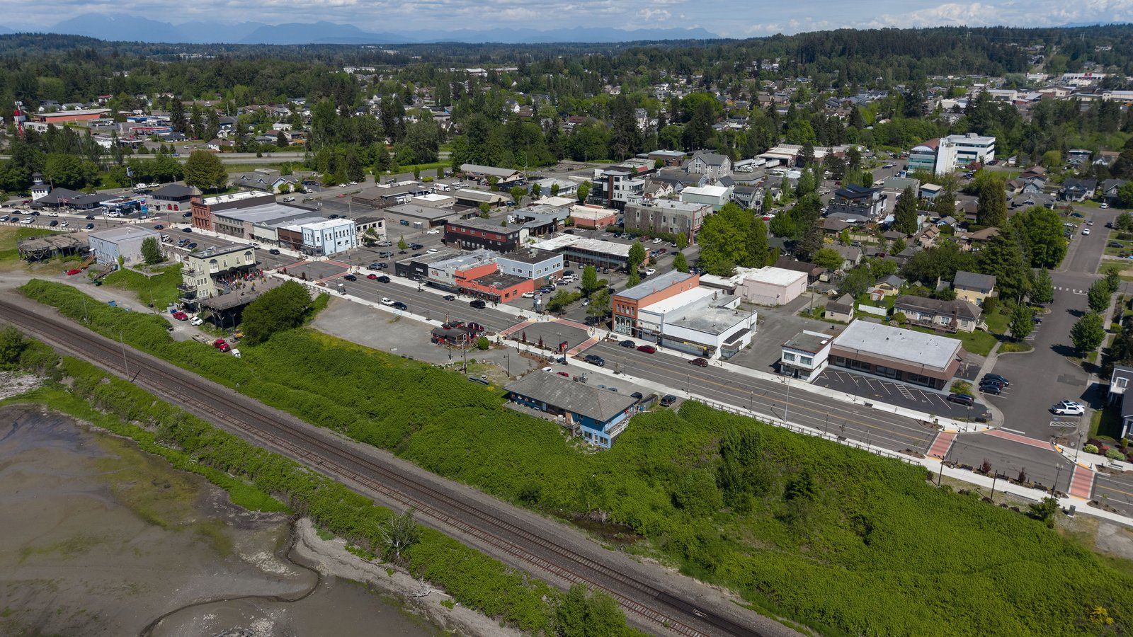 Aerial view of downtown Blaine along Peace Portal Drive, with shops and parking lots beside the railroad tracks and tideflats.