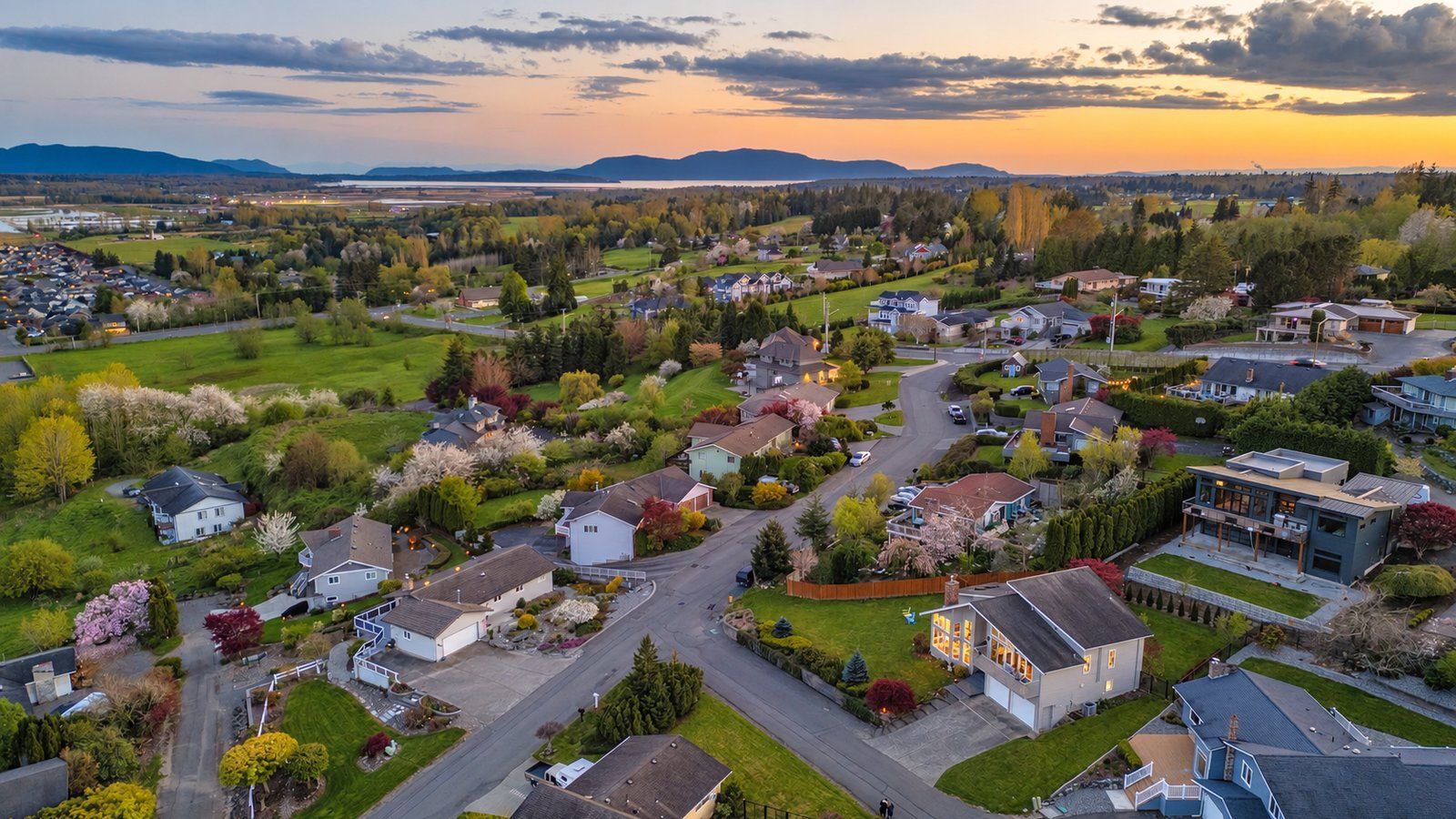 Sunset aerial view over a hillside neighborhood in Ferndale, Washington, with blossoming trees and the bay and islands in the distance.