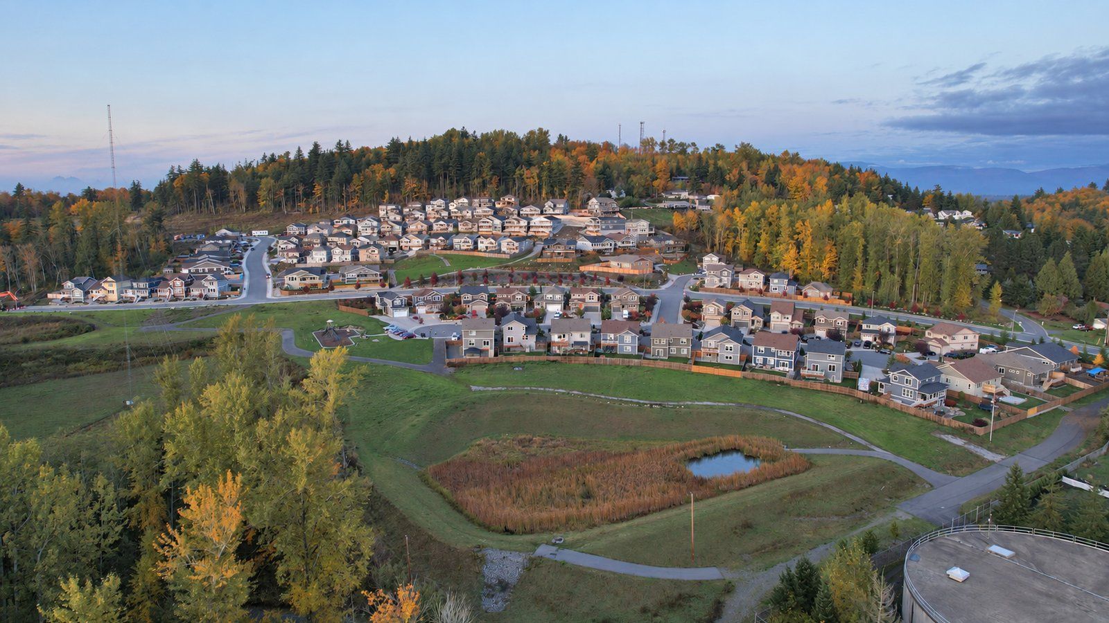 Fall aerial view of hillside subdivisions in Bellingham's King Mountain neighborhood, with autumn trees, a wetland and walking paths.