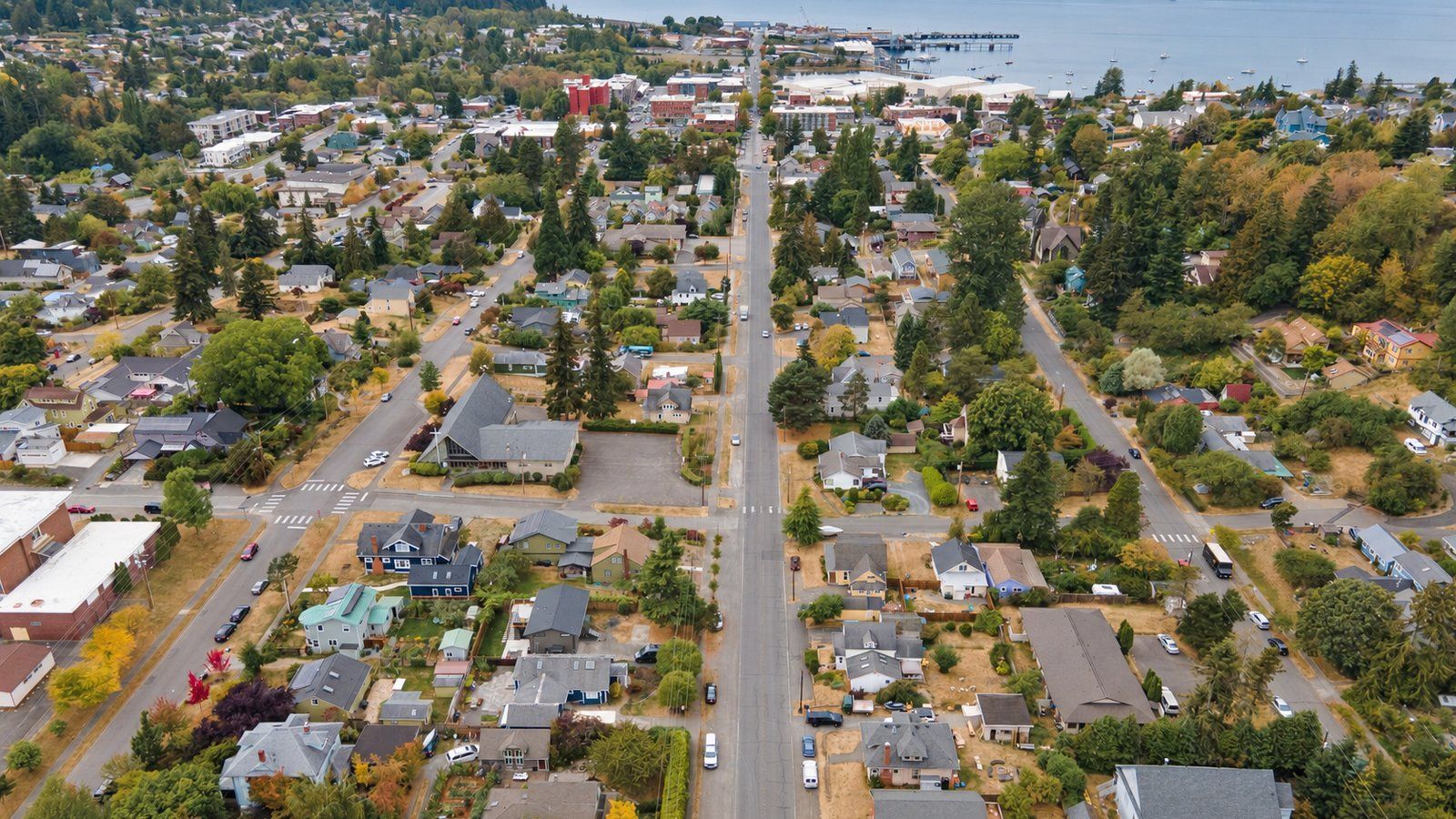 Aerial view down a long straight street through older Bellingham neighborhoods toward downtown Bellingham and Bellingham Bay.