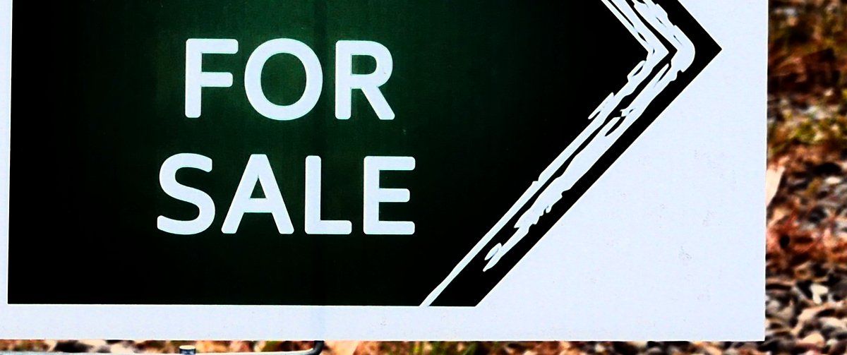 A green real estate 'For Sale' sign, illustrating the cost to sell a house in Washington State.