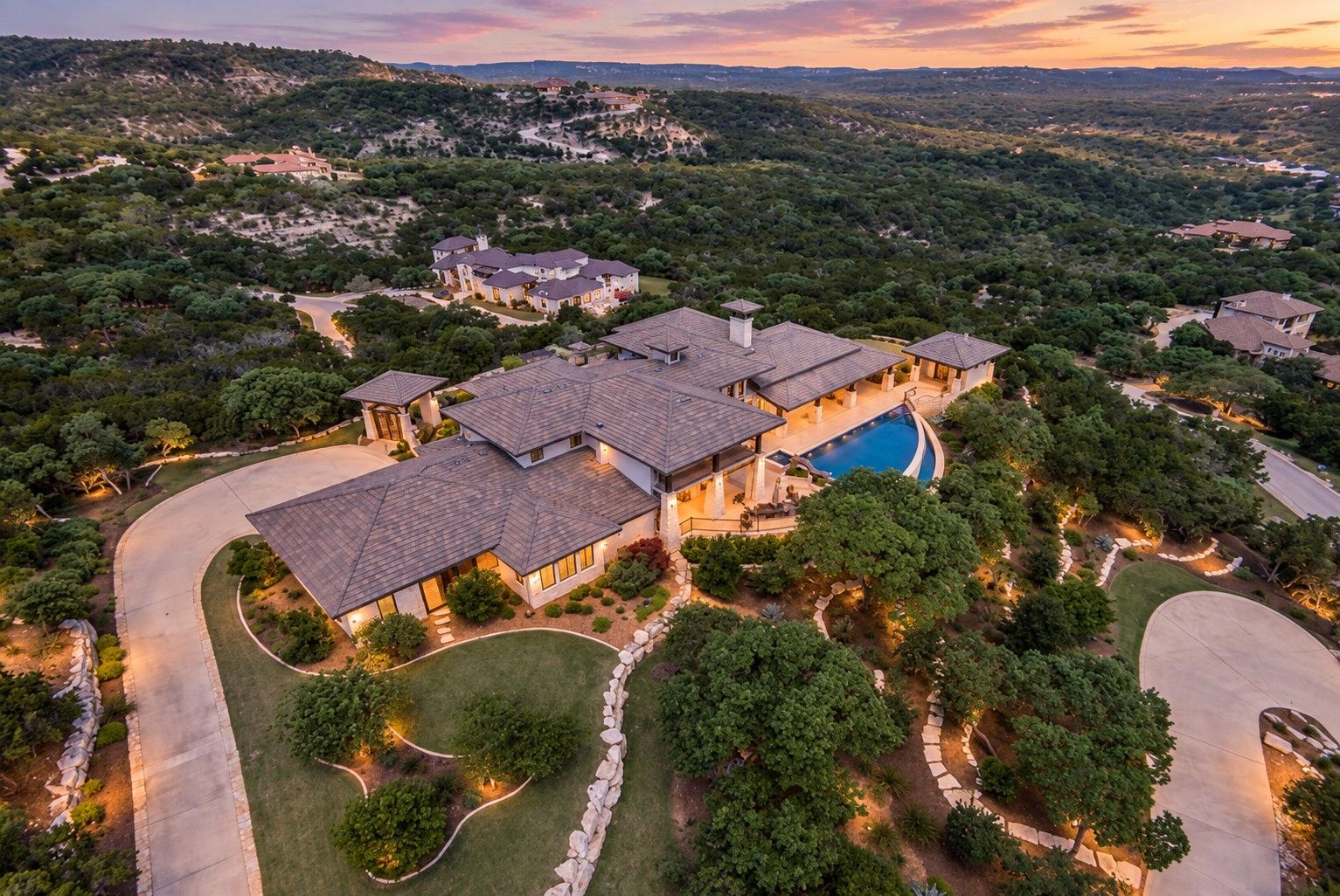 25018 Miranda Ridge, Anaqua Springs Ranch – aerial view of the estate, pool and Hill Country at sunset