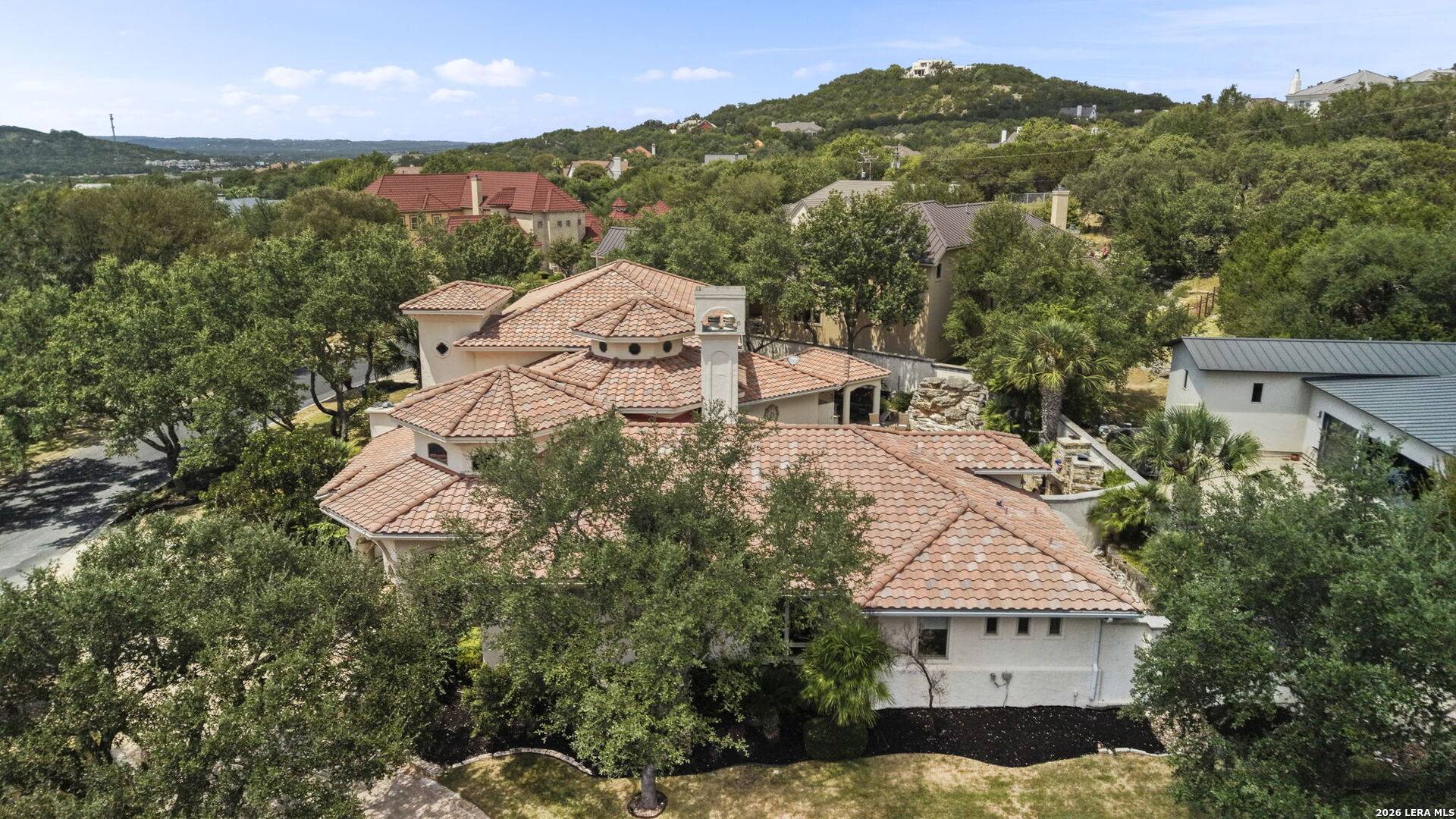 Aerial view of 2 Belcourt Place showing the tile roof and the wooded greenbelt behind the property