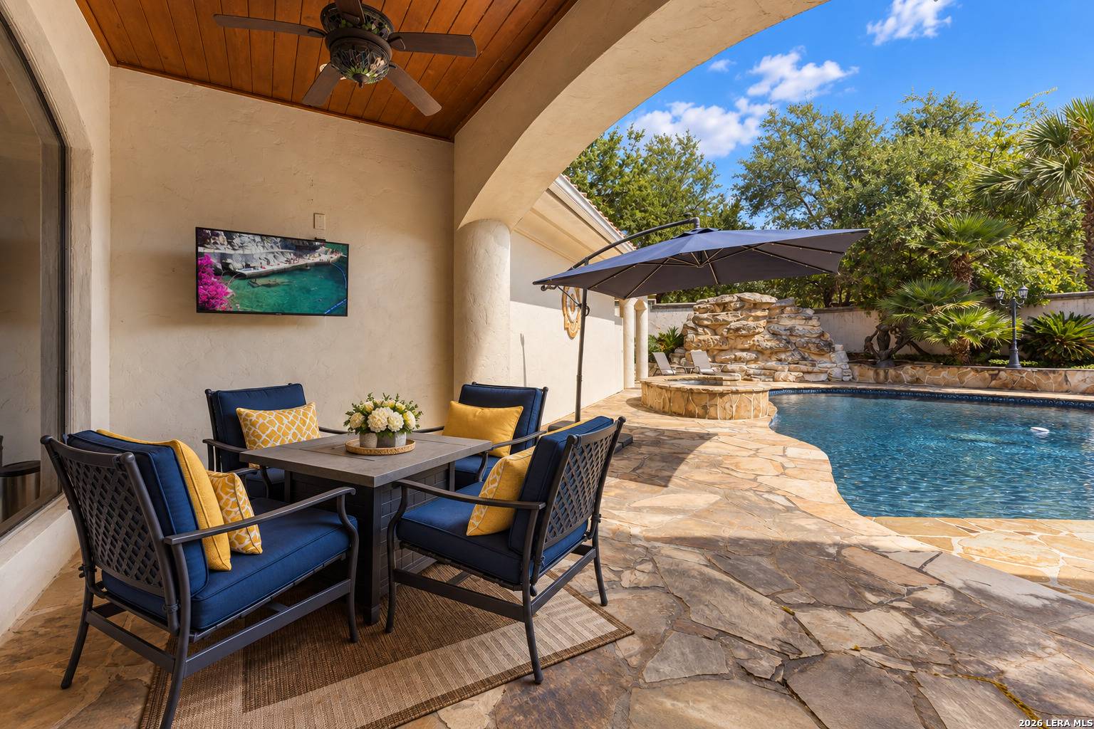 Covered outdoor living area with seating overlooking the pool at 2 Belcourt Place