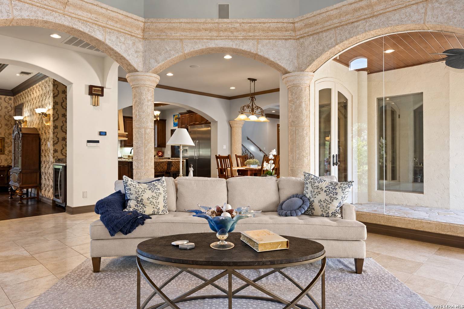 Family room of 2 Belcourt Place with stone columns and walls of glass opening to the covered patio