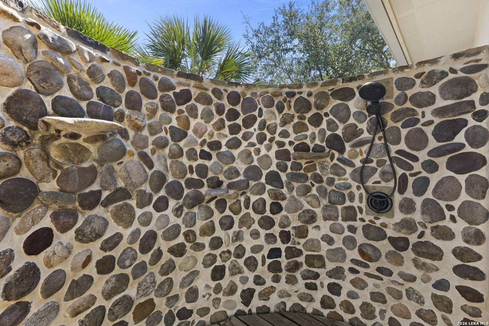 Private river-stone outdoor shower off the primary suite at 2 Belcourt Place