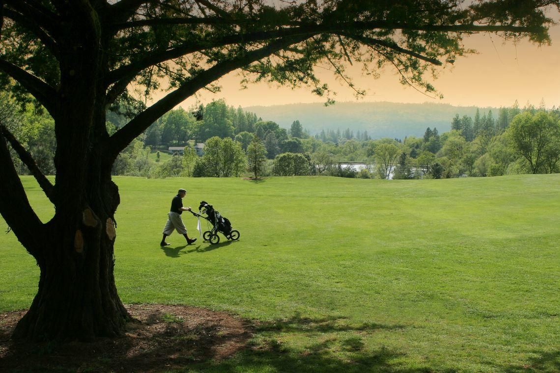 Golfer walking a green fairway at sunset near Alta Sierra in Nevada County CA
