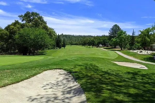 Lush green golf course fairway surrounded by pine trees in the Sierra Nevada foothills