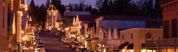 Historic downtown Nevada City lit up at night, a lifestyle contrast to gated Lake of the Pines