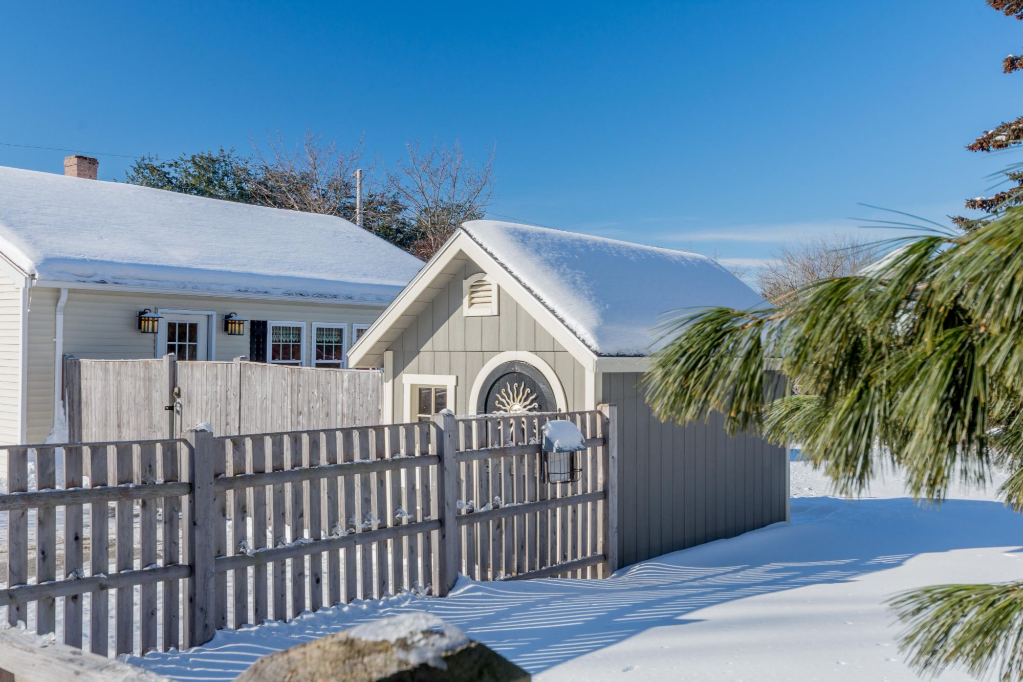 Snowy Backyard in Portland Maine with a shed, fence, and evergreen