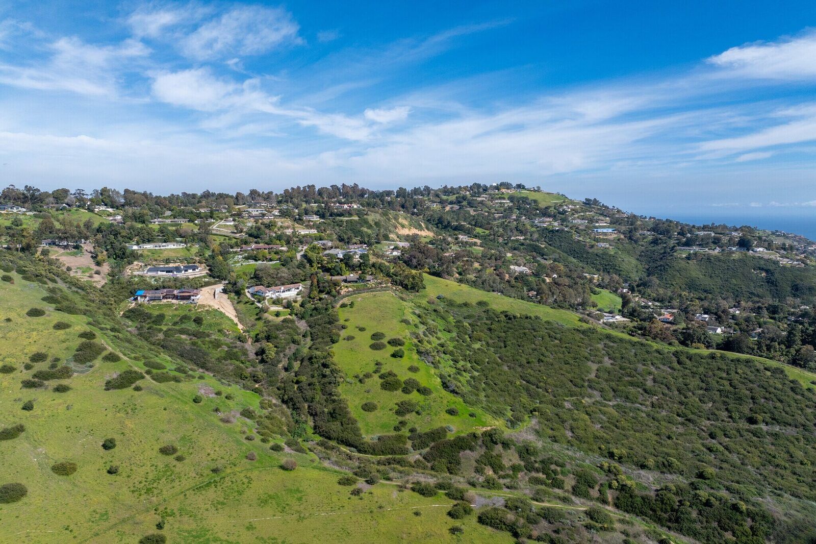 Open green hillside with custom homes in gated Rolling Hills