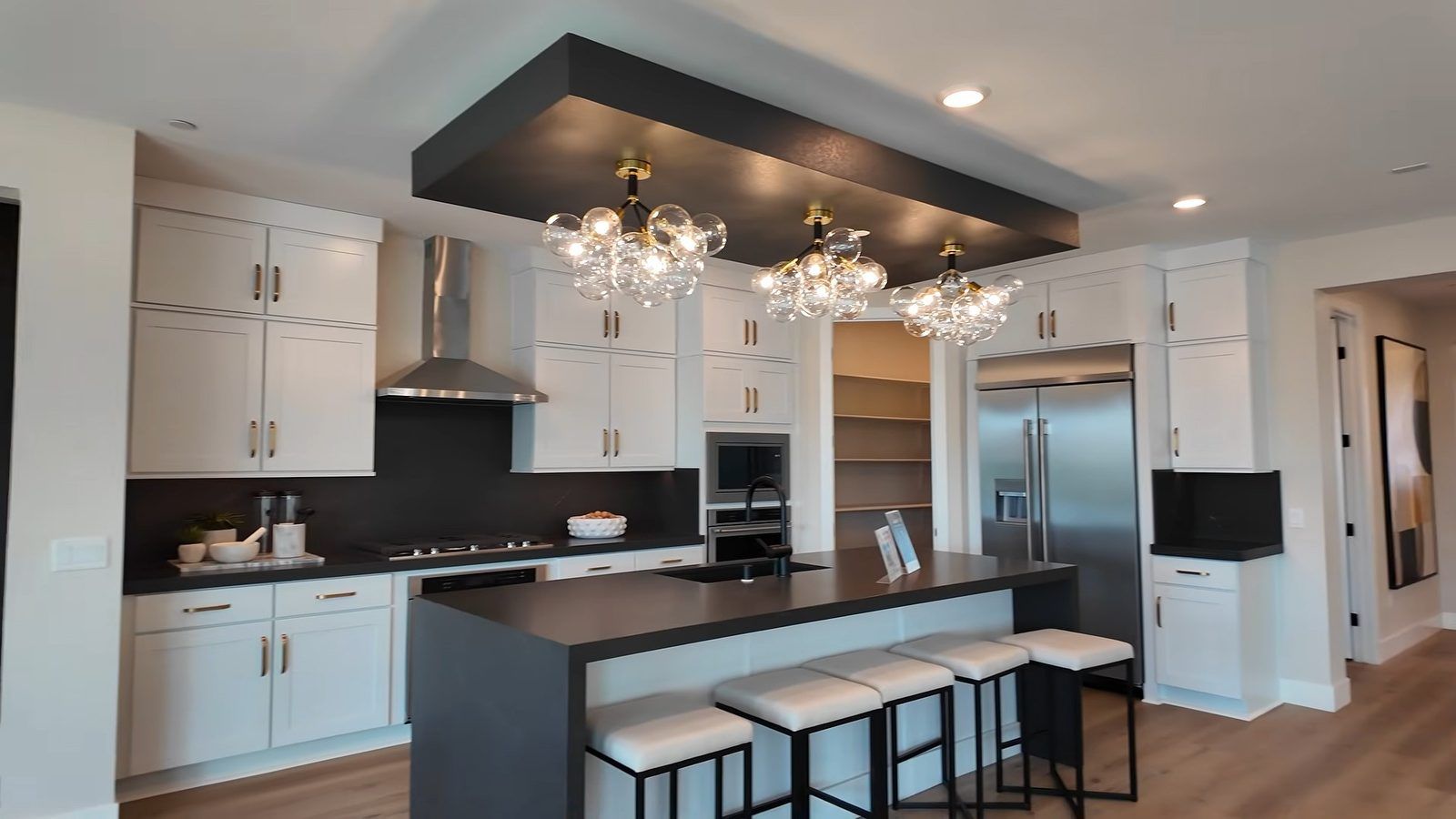 Parklane model kitchen with white shaker cabinets, a dark waterfall island with seating, and stainless built-in appliances