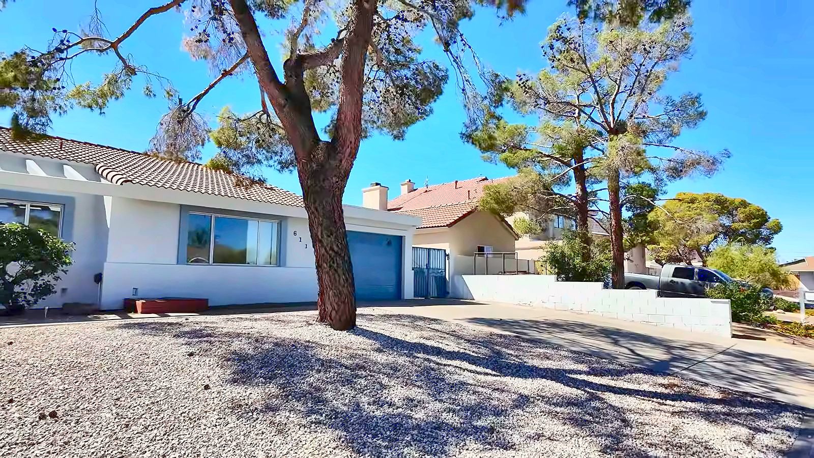 Front exterior of a single-story resale home in Las Vegas with mature trees and desert landscaping