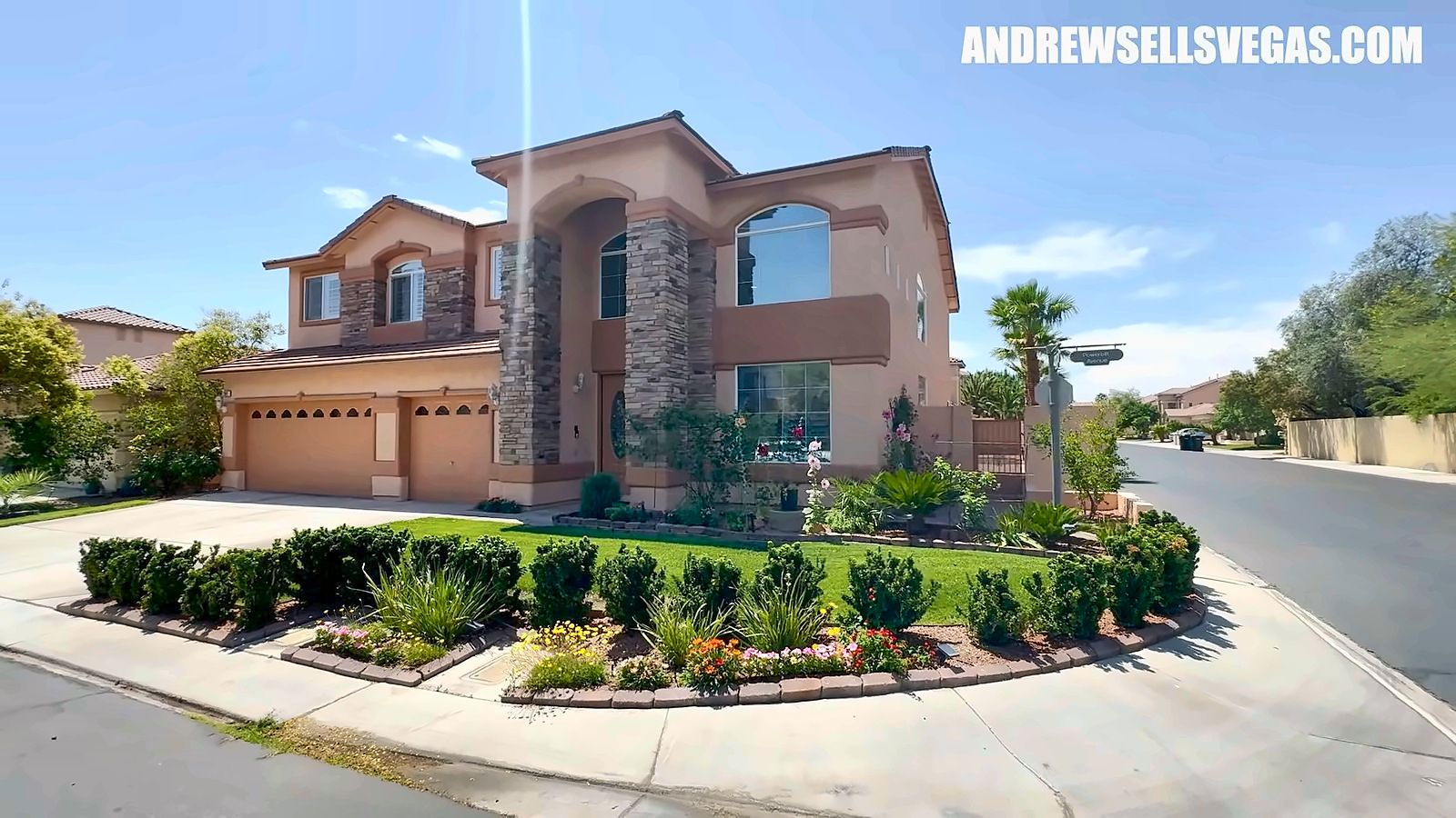 Front of a two-story stucco home with a stone accent, tile roof and landscaped yard in Rhodes Ranch