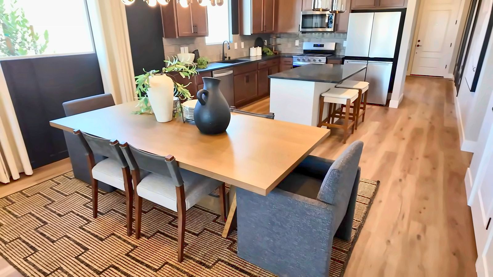 Dining area and kitchen in the Pulte Hewitt model with a wood dining table, dark cabinets, and an island