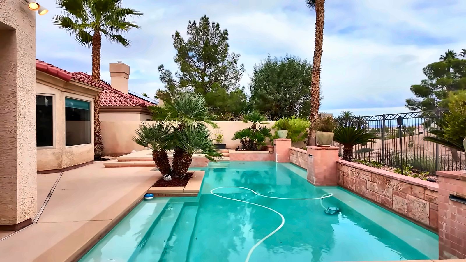 Backyard pool behind a Rhodes Ranch home with a view fence and the golf course beyond