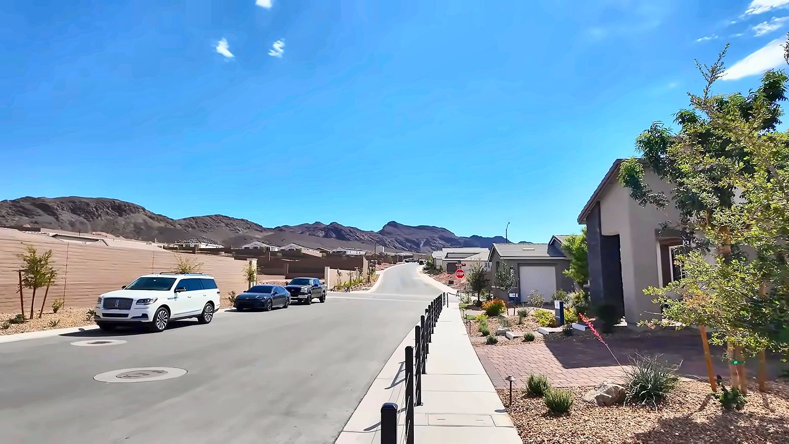 New neighborhood street in Aries, east Henderson NV, with sidewalks, young landscaping, and desert mountains in the background