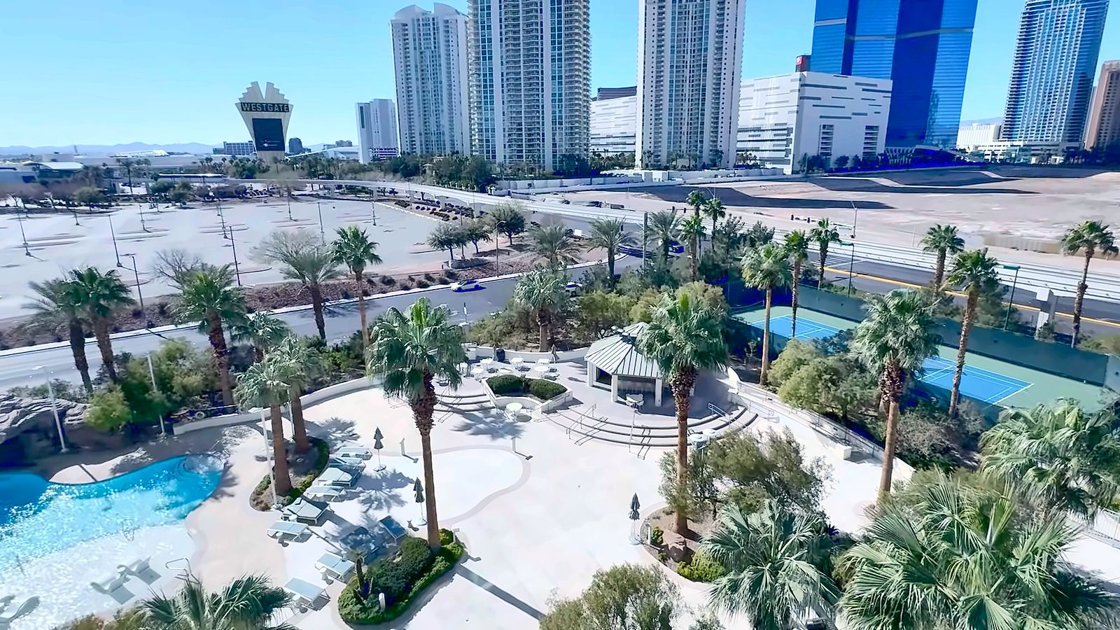 Resort-style pool, palm-lined courtyard and tennis courts at Turnberry Towers with Las Vegas high-rises beyond