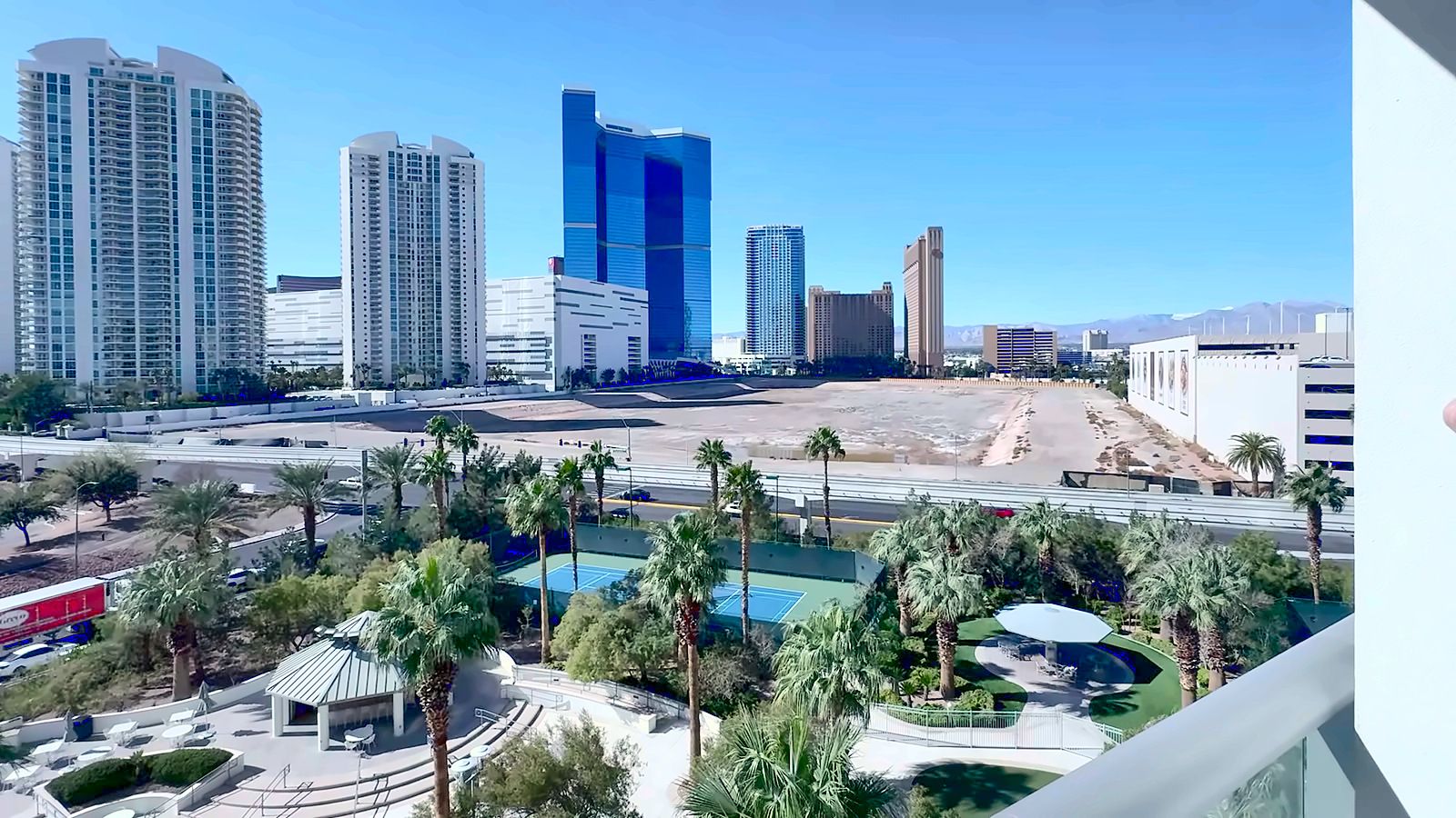 View south toward Las Vegas Strip towers over palm trees and the Turnberry Towers pool courtyard from a 6th-floor terrace