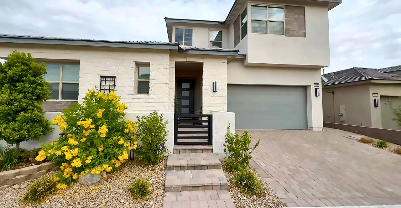 Two-story modern home with desert landscaping and yellow flowering shrubs in Summerlin, Las Vegas