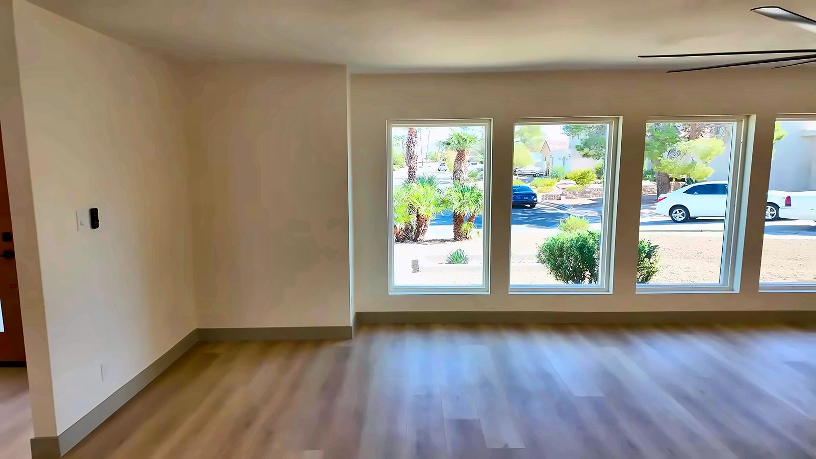 Empty, freshly painted living room with wood-look flooring and a wall of windows in a Henderson home