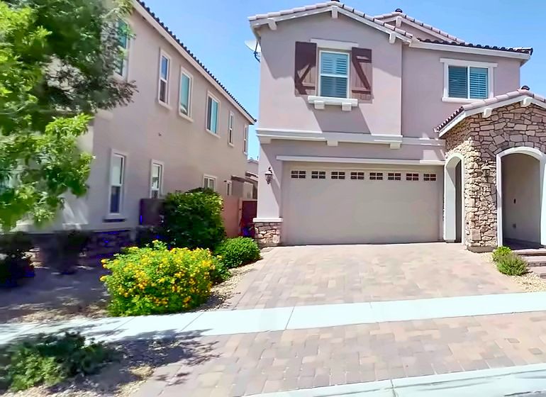 Two-story stucco home with stone accents and a paver driveway in Inspirada, Henderson