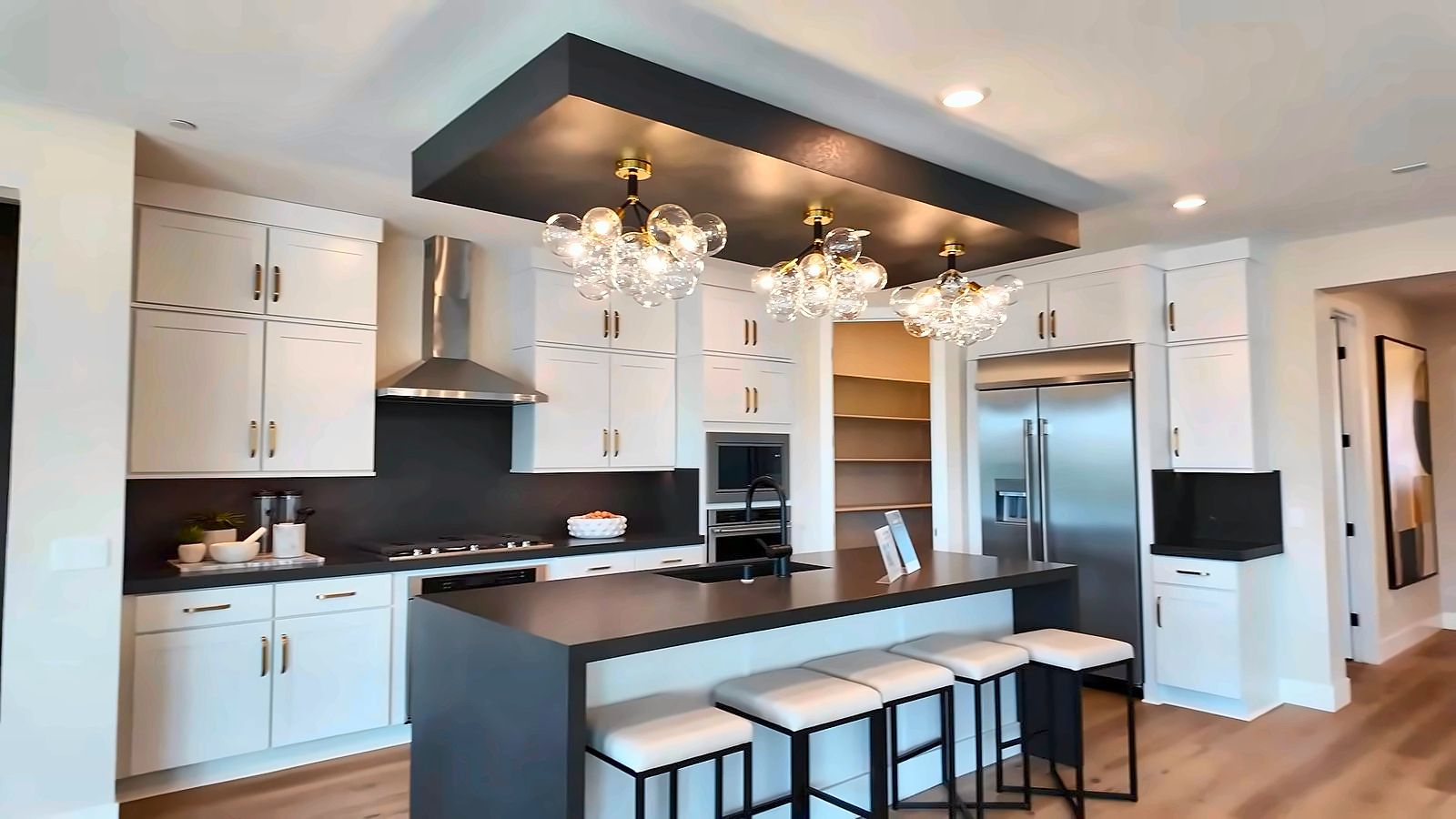 Parklane model kitchen with white shaker cabinets, a dark waterfall island with seating, and stainless built-in appliances