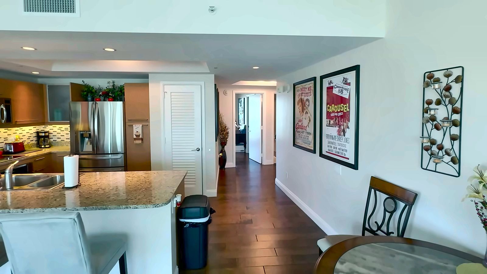 Granite kitchen counter with bar seating open to a dining area and hallway in a Turnberry Towers condo