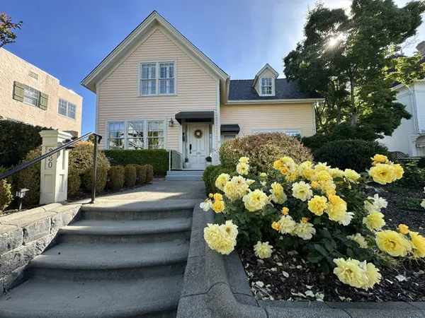 Pretty older home with light yellow paint and yellow roses in front in Petaluma CA