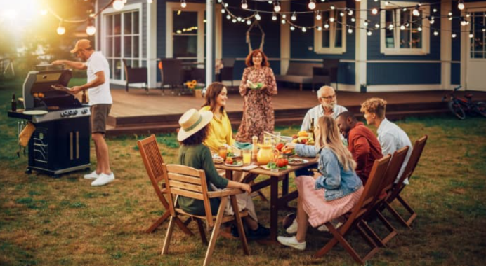 Friends and family gathered around an outdoor dining table while grilling during a summer afternoon in a Harrisonburg backyard.