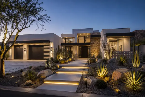 Modern luxury home at twilight with illuminated desert landscaping in Scottsdale Arizona