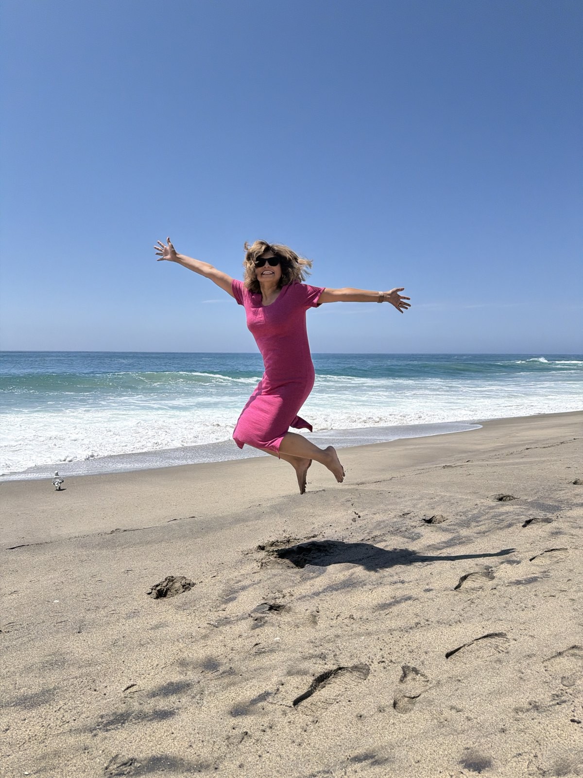 Jasmine Sayeed, REALTOR®, jumping for joy at Treasure Island Beach in Laguna Beach
