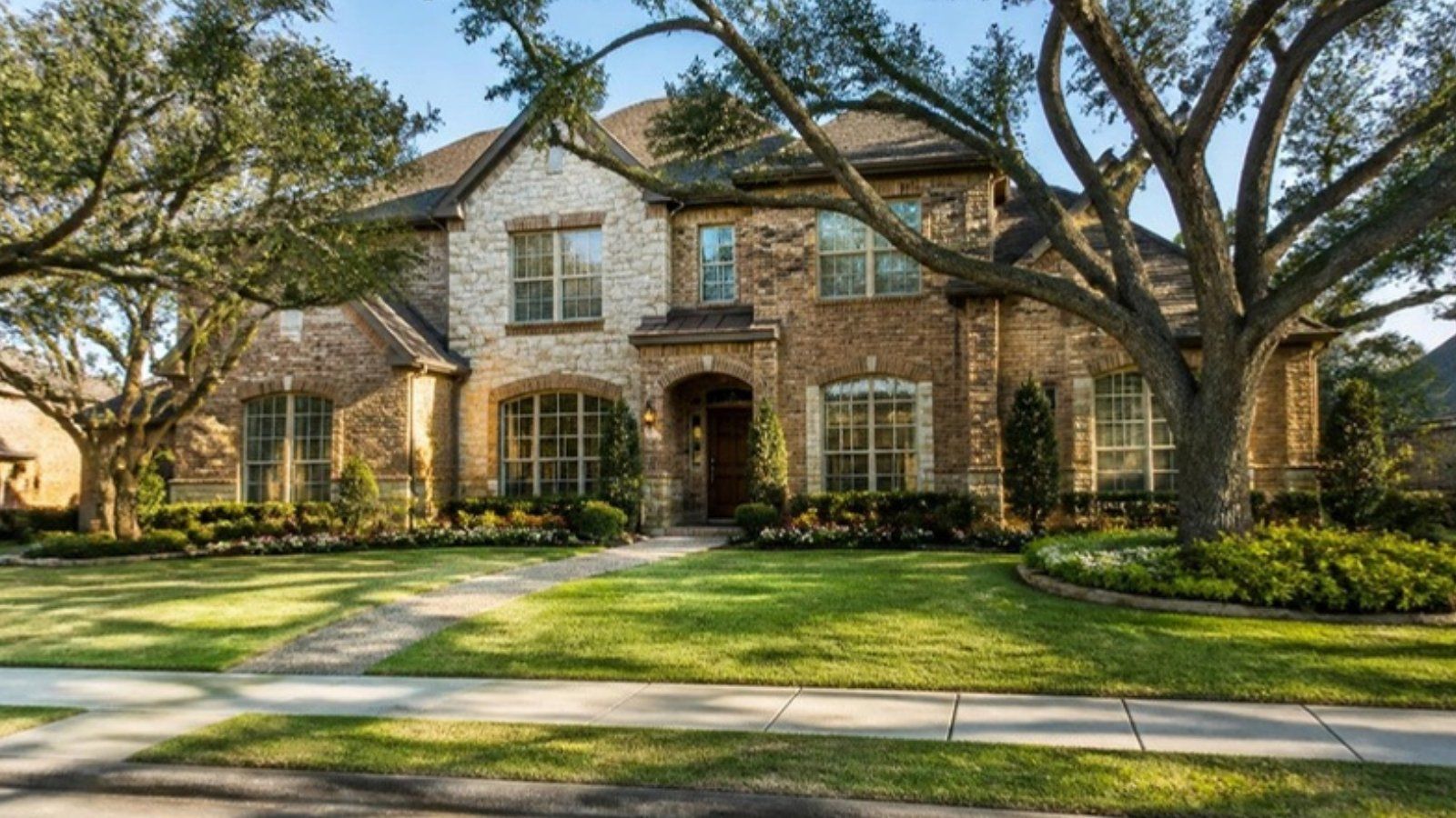 Established two-story brick and stone home with mature oak trees, typical of resale homes in the Fulshear, TX area