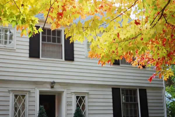 Classic white colonial home with picket fence and autumn foliage, representing home buying services in Winchester, VAbuyer-services