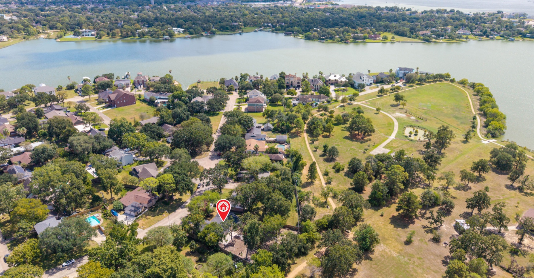 Aerial neighborhood view with an approximate property-location marker, park space, and the nearby lake.