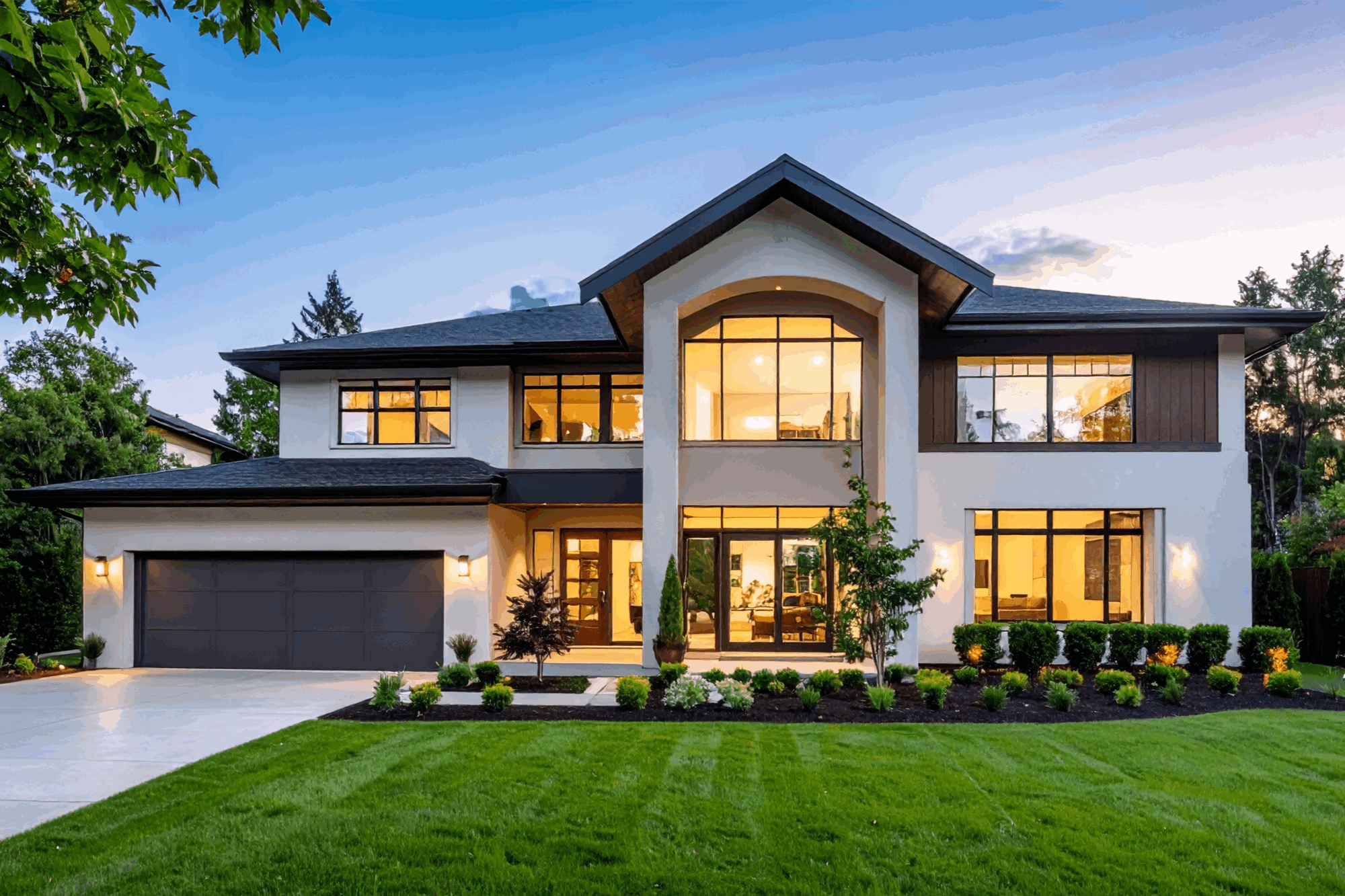 Modern hillside home with wide glass walls and outdoor living space at dusk