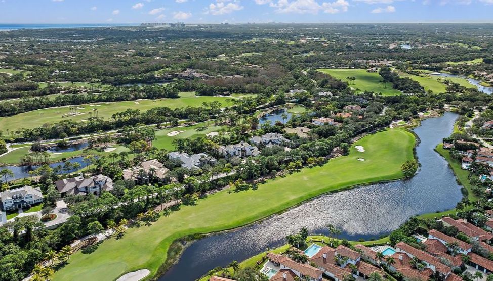 Florida golf green with mature trees and palms representing The Bear's Club lifestyle