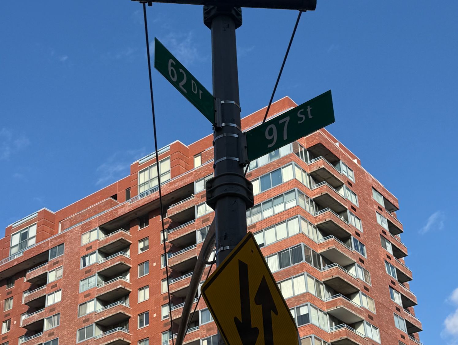 Rego Park street sign at 62nd Drive and 97th Street in front of a high-rise Queens co-op building