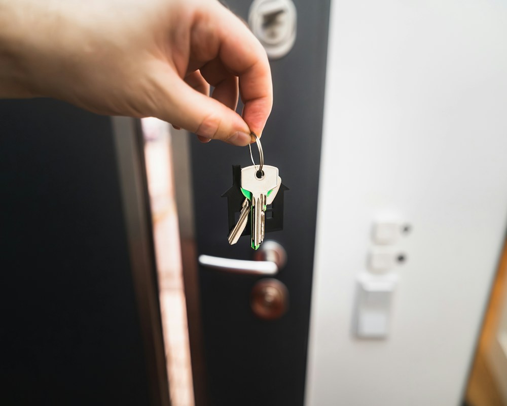 A house key held in front of a front door