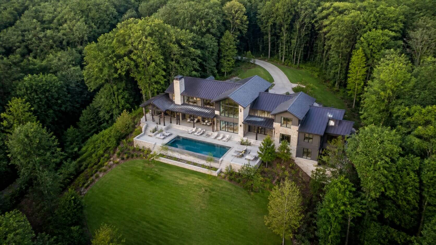 Aerial view of a North Alabama home with a pool surrounded by mature trees