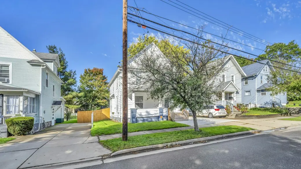 Two-story home with a covered front porch on a tree-lined street