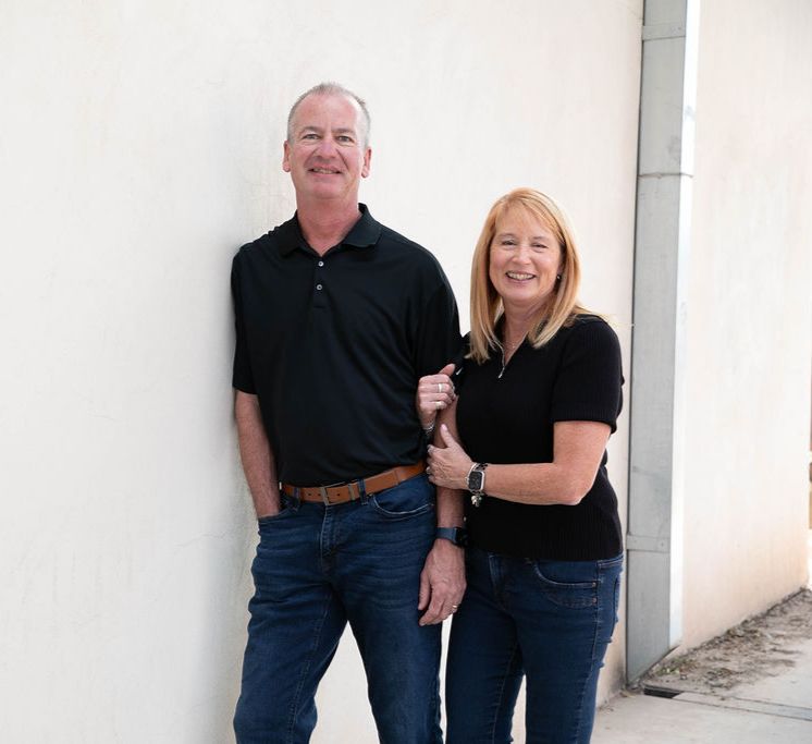 Paul and Darci Dunn, Tucson real estate and relocation specialists with eXp Realty, standing together outside a home in Tucson, Arizona.