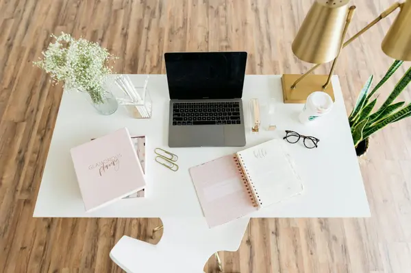 Bright, organized home office desk with a notebook and laptop
