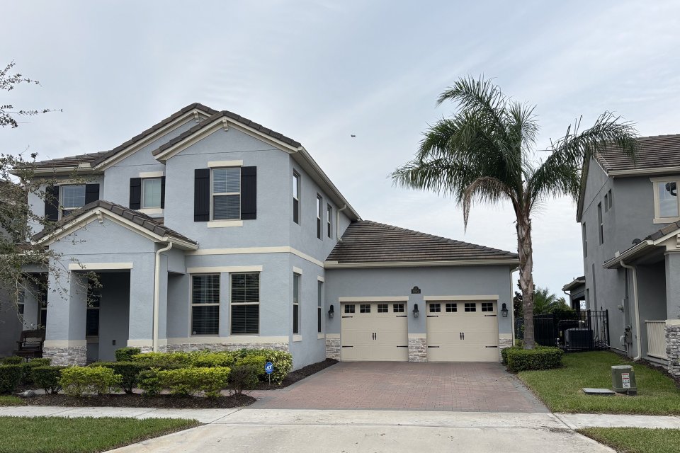 Two-story stucco home with a tile roof and paver driveway on a Winter Garden area street