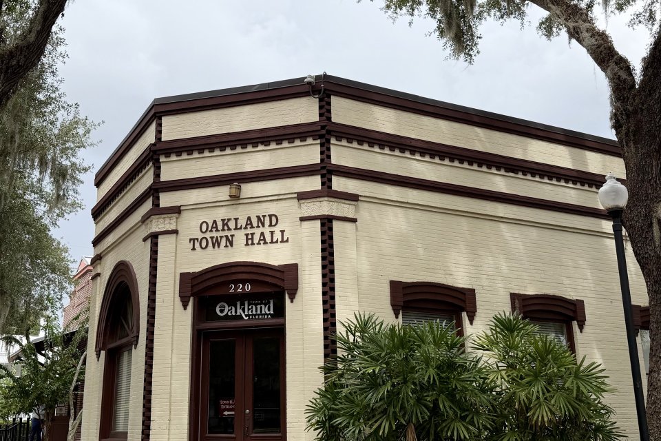 The historic Oakland Town Hall building with a live oak in Oakland, Florida